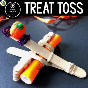 Treat Toss Catapult STEM Challenge Activity built with craft sticks, rubber bands, highlighter and candy pumpkin.