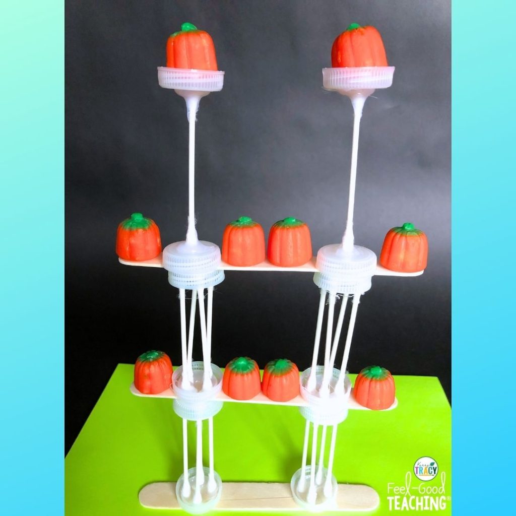 Pumpkin pedestals STEM design made of cardboard, straws and foil holding up pumpkin candies.