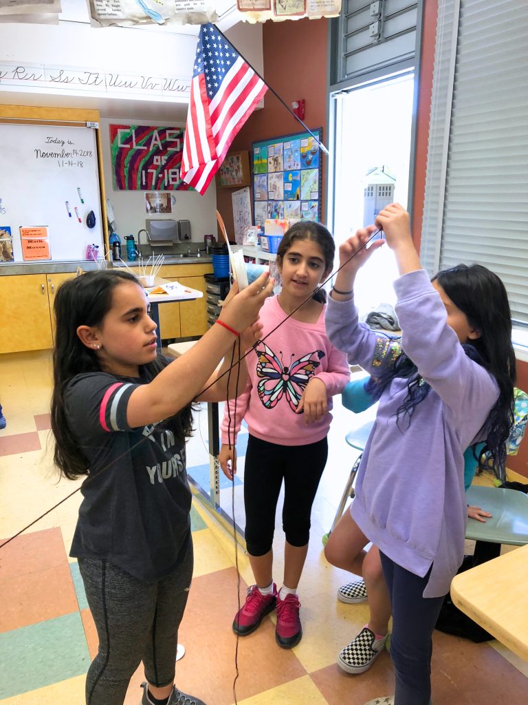 A small group of students working together to construct a way to safely transport a turkey in this fun STEM activity for Thanksgiving.